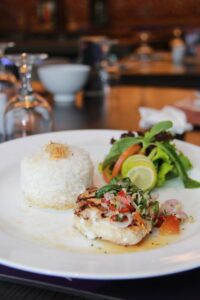 Plate with delicious fish with herbs and rice placed on table in restaurant