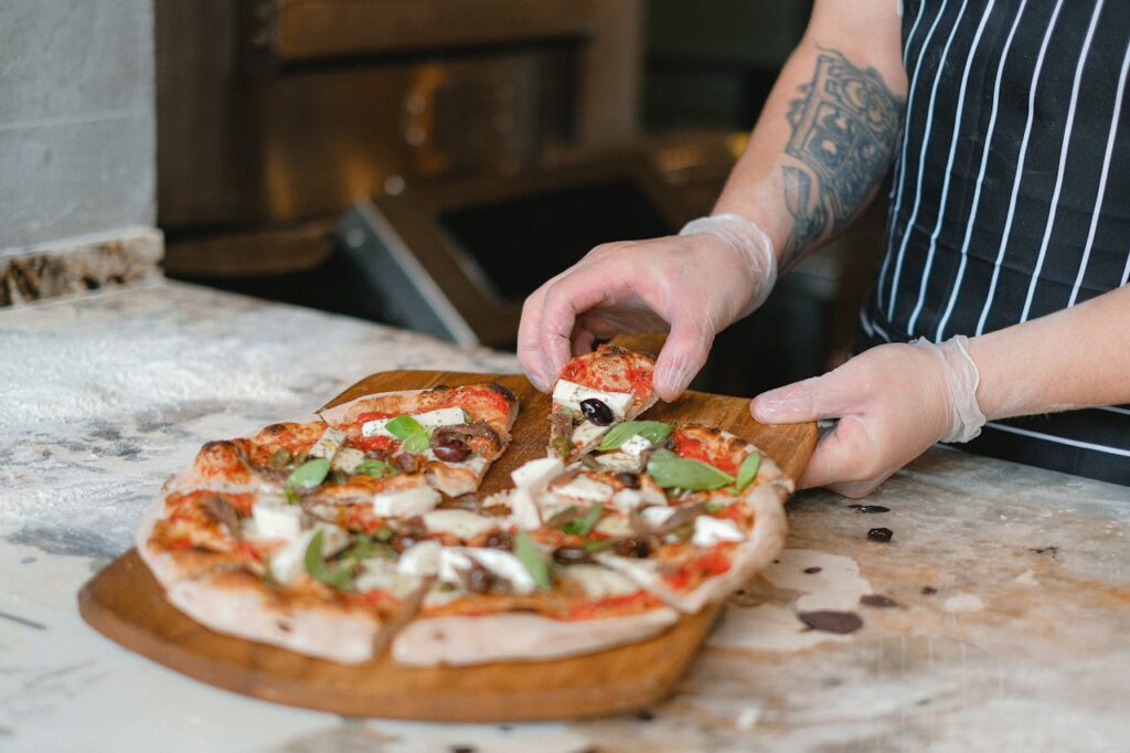 Close-up of a chef slicing a freshly baked artisan pizza in a kitchen setting.