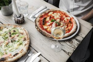 Appetizing pizzas with white wine served on a rustic wooden table, perfect for culinary enthusiasts.